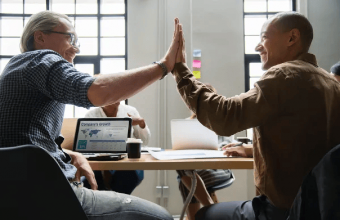 Two employees high-fives in office