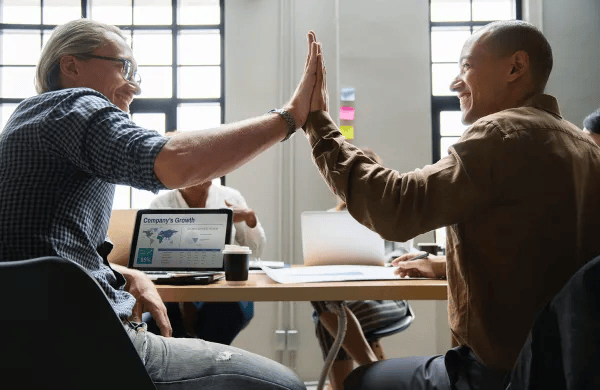 Two employees high-fives in office
